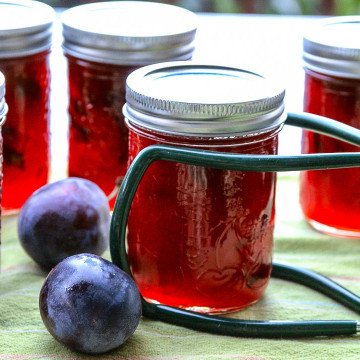 Jars of jam on a table, with plums