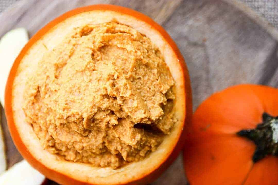 A close up of hummus dip in a hollowed-out pumpkin