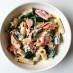 Salmon & spinach pasta in a white bowl.