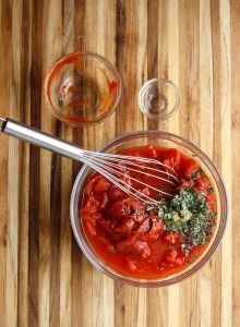 Tomato sauce ingredients in a glass bowl being whisked together.