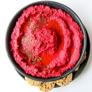 Beet hummus in a black bowl.