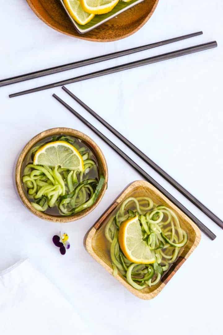 2 wooden bowls of sunomono salad and two sets of black chopsticks