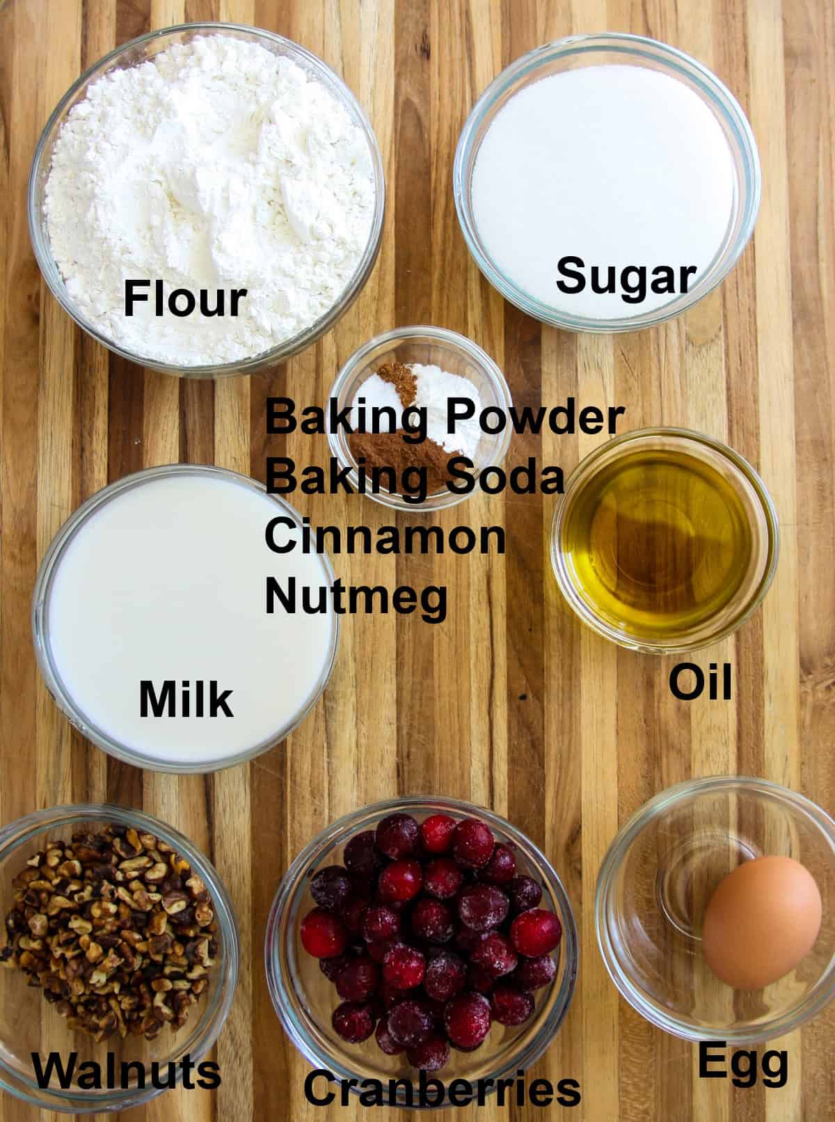 The ingredients for making cranberry walnut bread on a wood board.