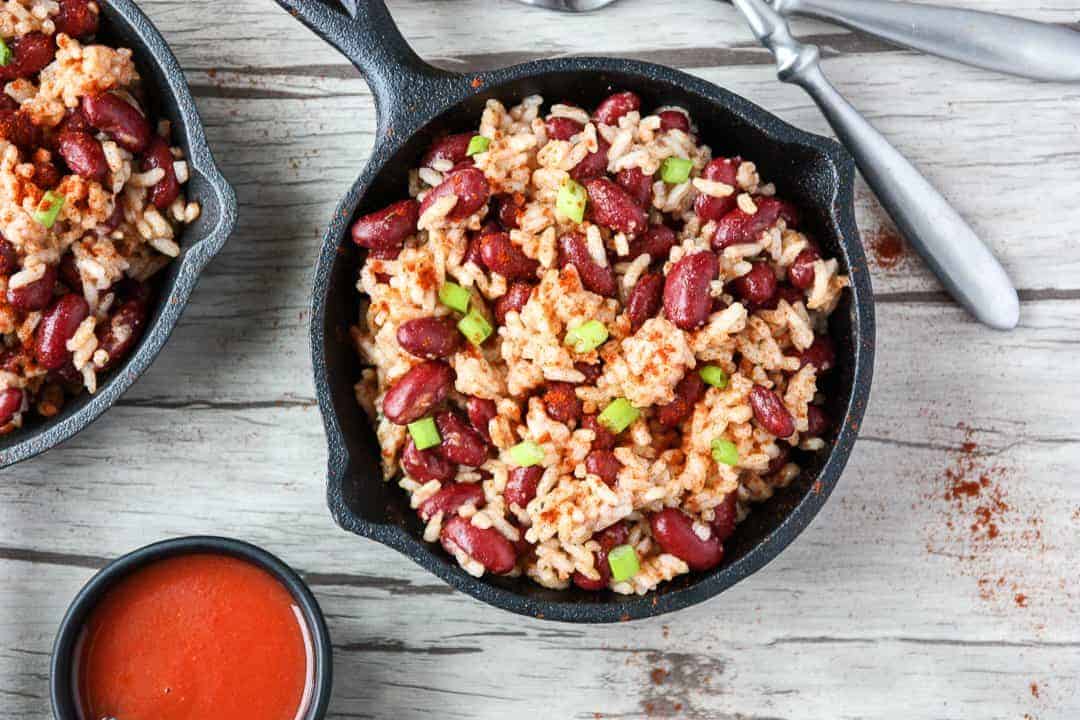 Red beans and rice in small black skillet on wooden table