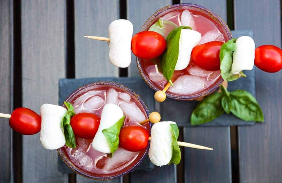 Two caesar drinks garnished with cherry tomatoes
