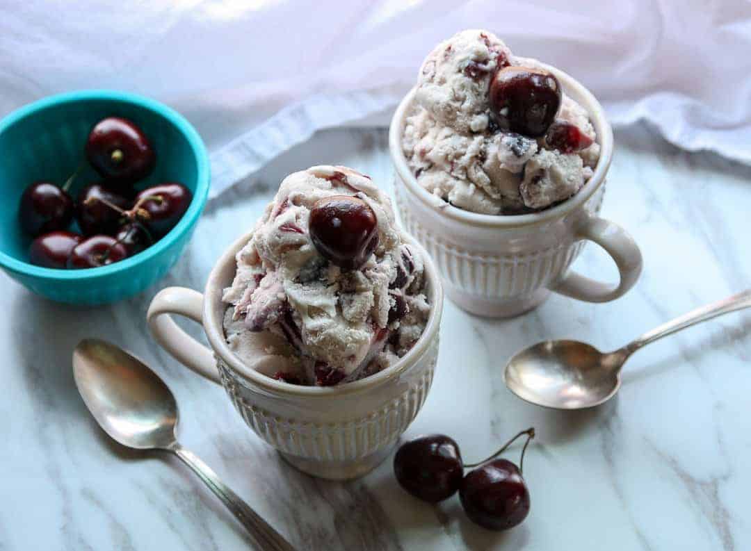 Two bowls of frozen dessert, with spoons on a marble countertop.