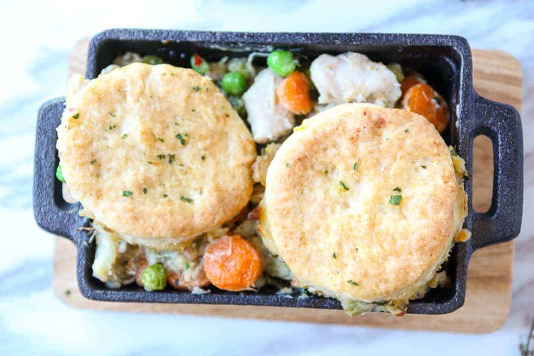 A pan of food, with chicken, carrots and peas
