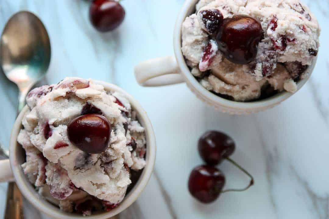 Two dishes of cherry amaretto ice cream with fresh cherries on top of each serving
