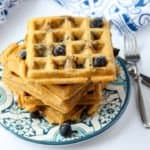 A stack of waffles on a plate, with blueberries