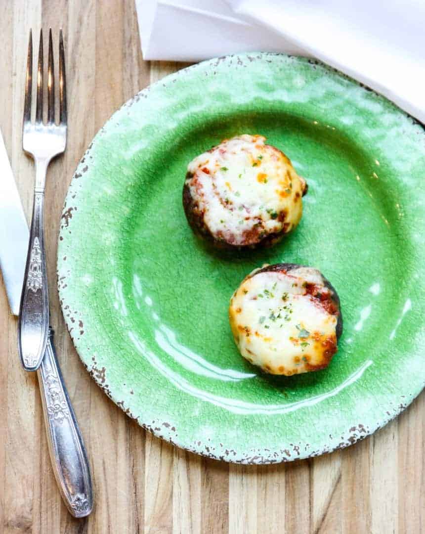 Two pizza stuffed mushrooms on a green plate