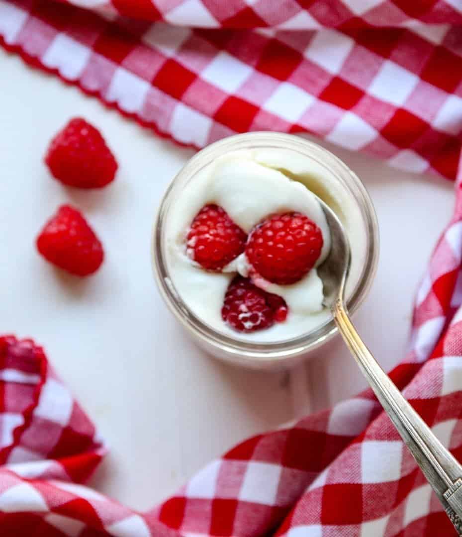 A close up of a jar of mousse with berries
