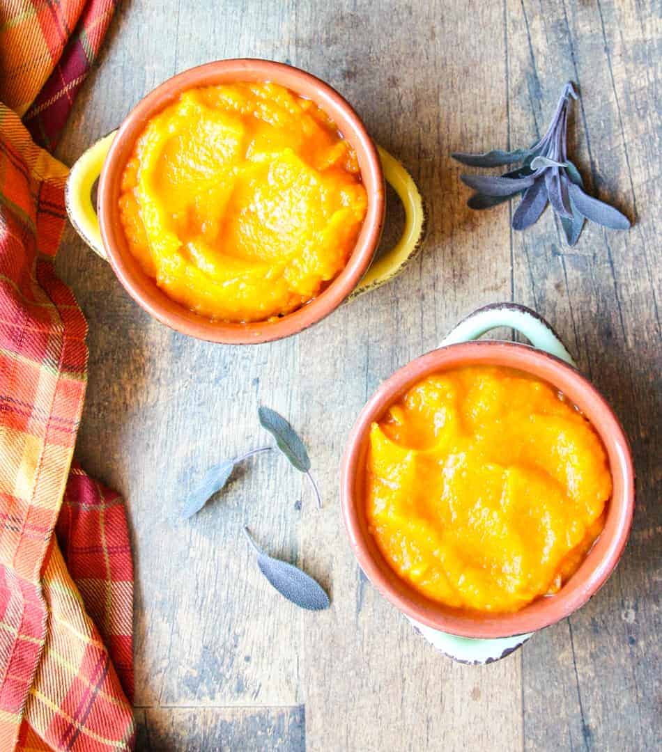 Two bowls of squash on a table with sage leaves