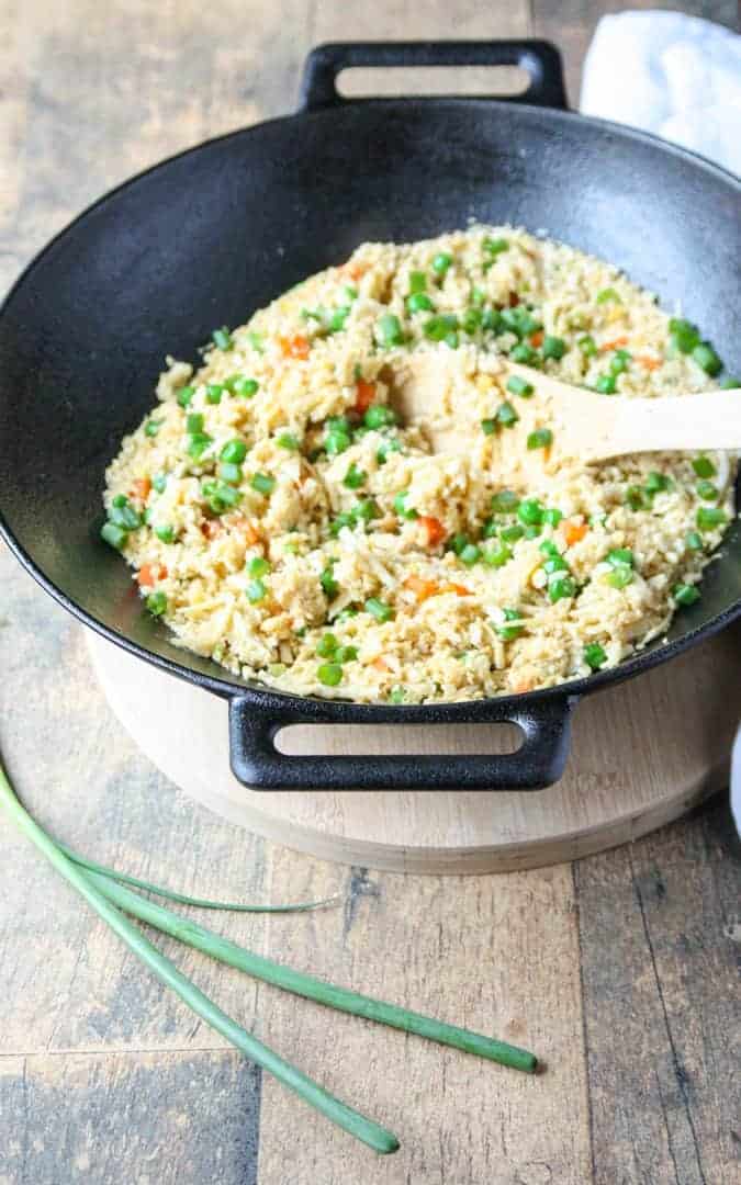 Cauliflower fried rice in a cast iron wok with wooden spoon