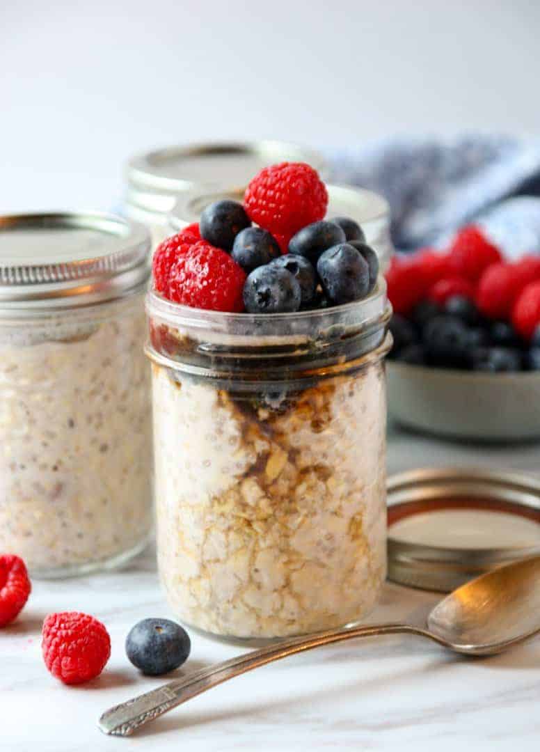 A close up of a jar of oatmeal topped with fruit