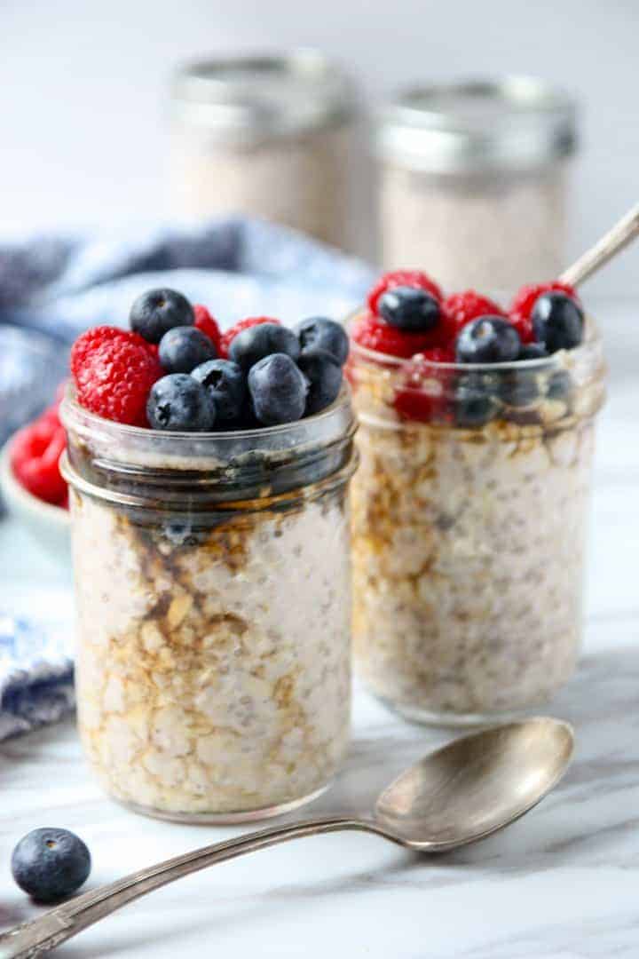 A close up of two jars of overnight oats with berries