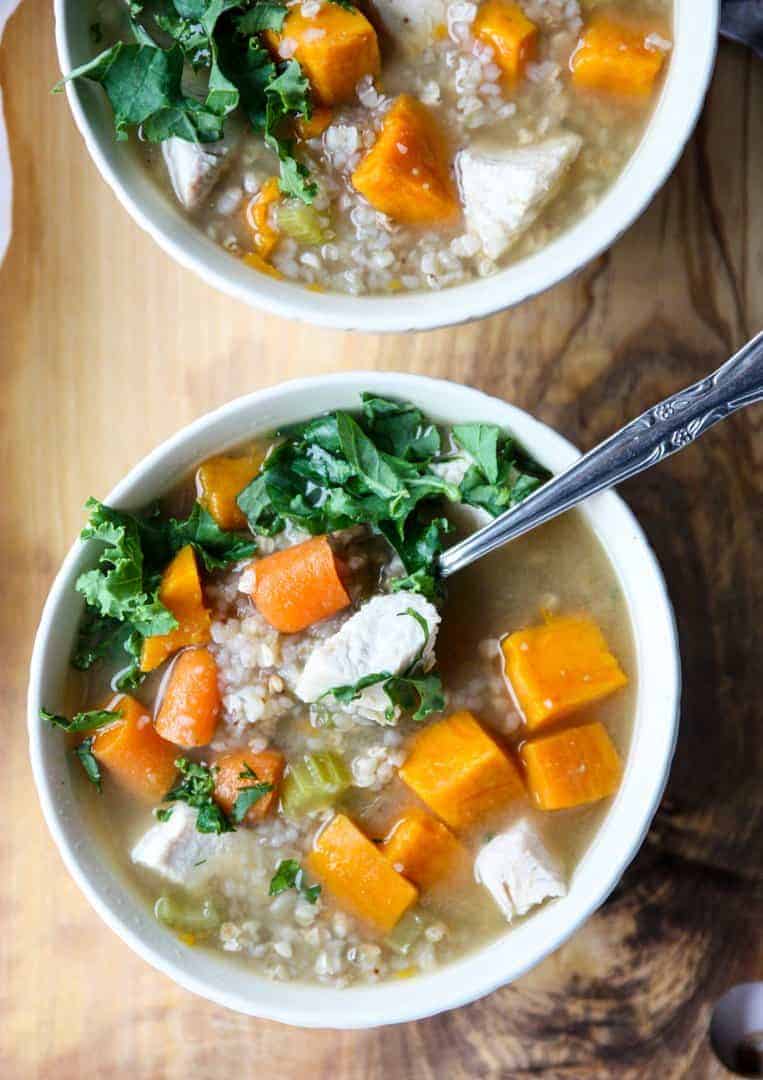 A bowl of soup on a table, with a spoon in it