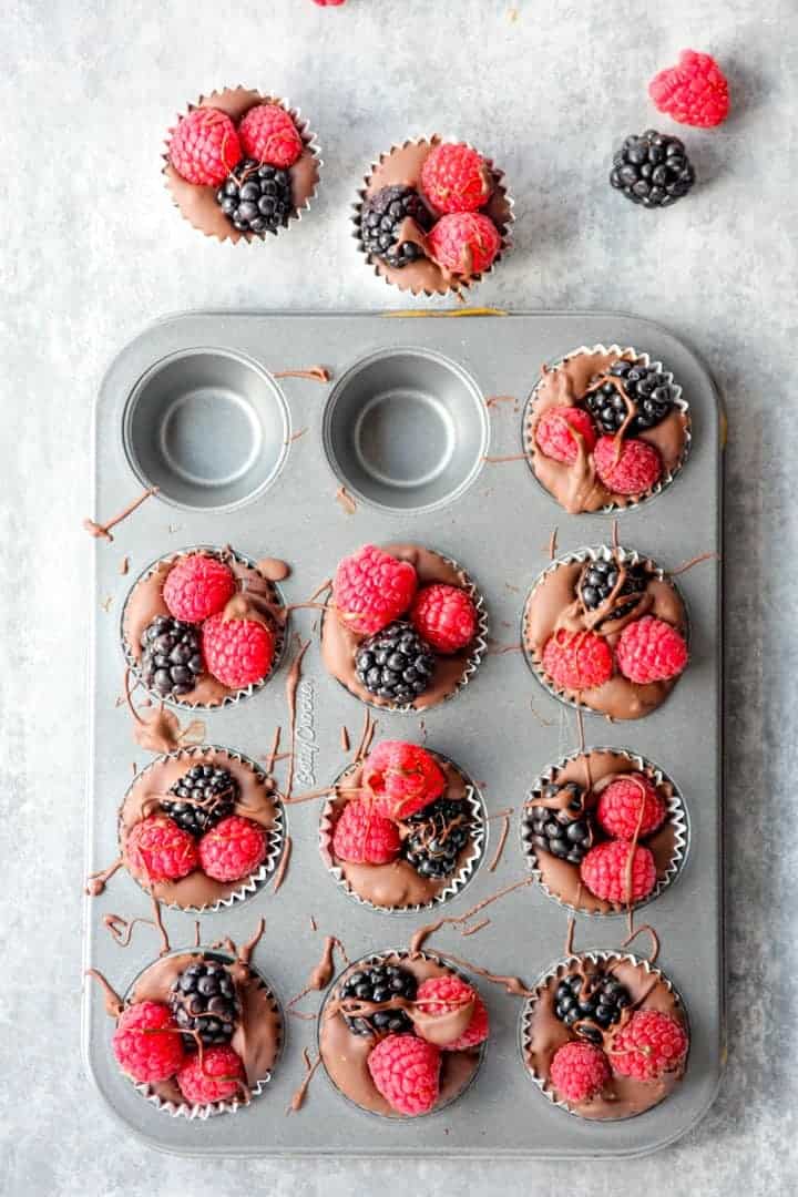 A muffin tin with homemade berry topped chocolates