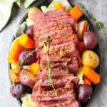 A round black plate of vegetables and sliced meat,