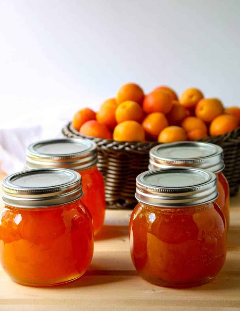 Four jars of jam with apricots in a basket