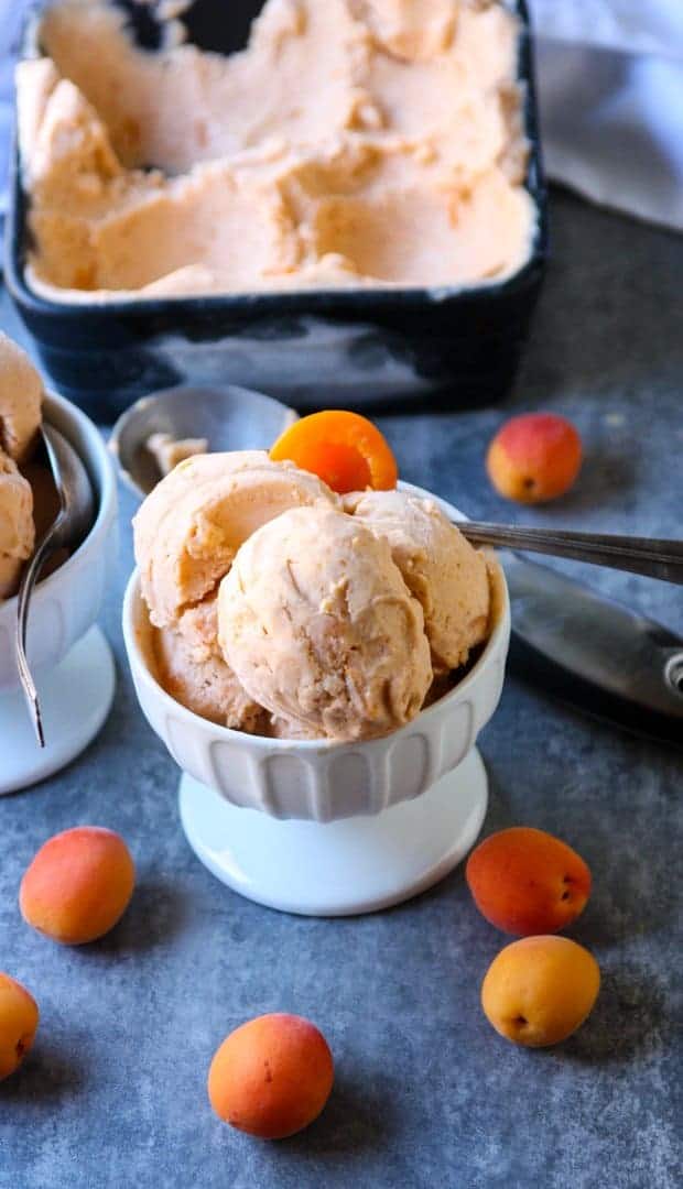 A bowl of ice cream on a table, with apricots