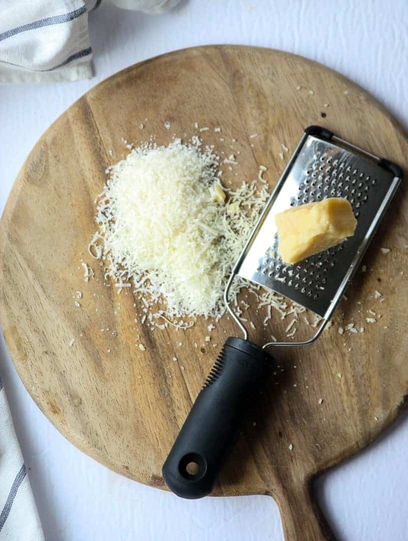 Parmesan Cheese being grated on a wooden board