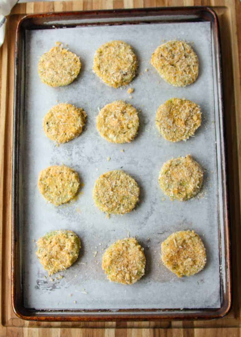 Breaded green tomato slices on a baking sheet