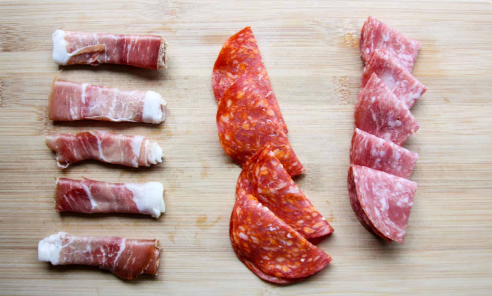 A variety of sliced deli meats on a wooden board