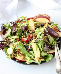 Salad ingredients being combined on a platter.