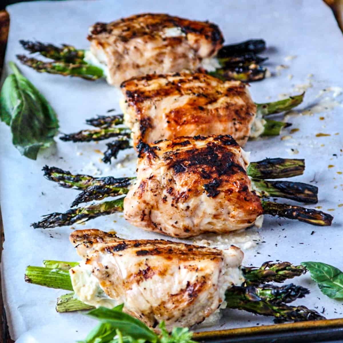 Grilled chicken stuffed with asparagus on a tray.