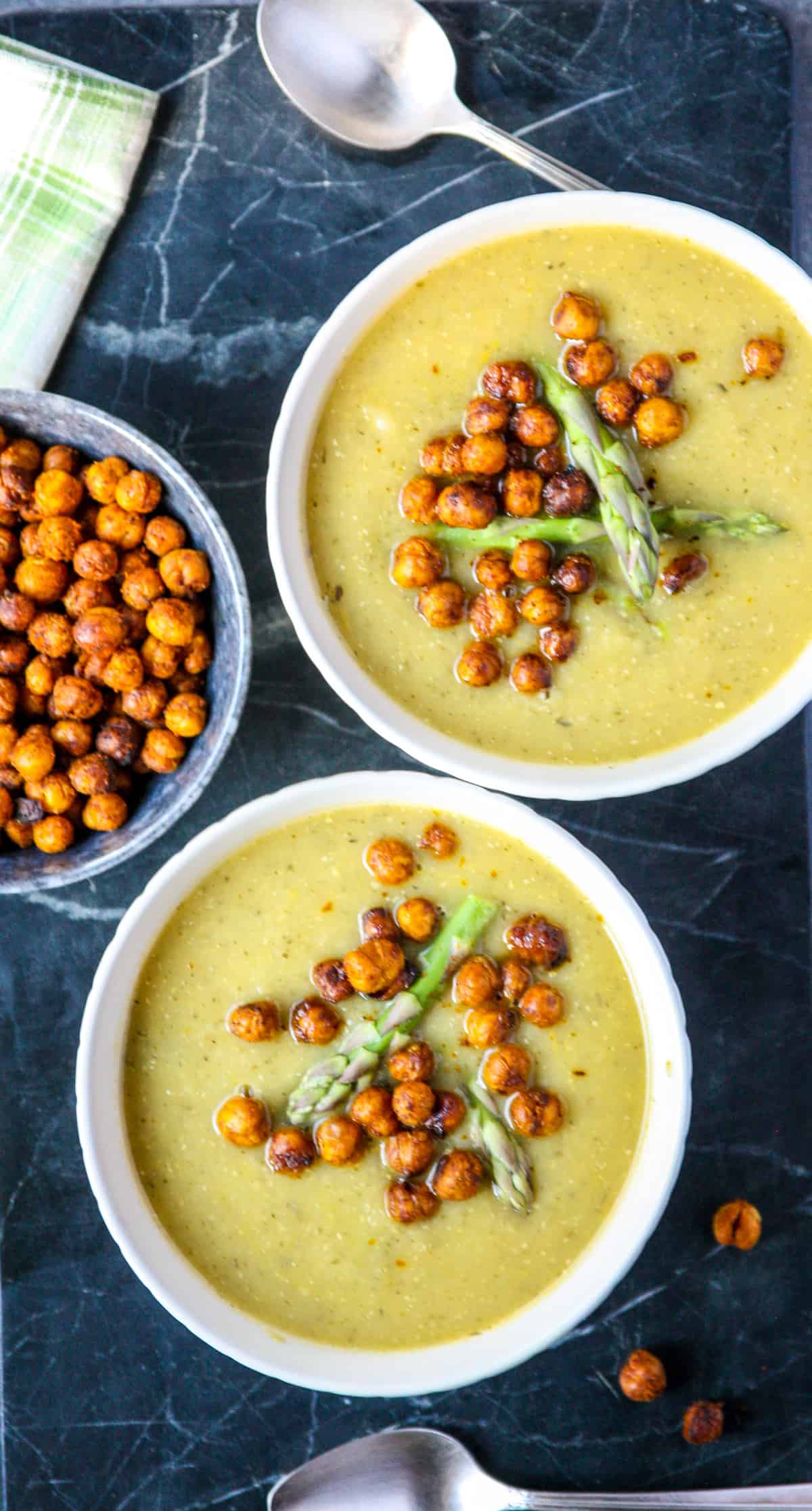 Two bowls of asparagus soup on a granite countertop.