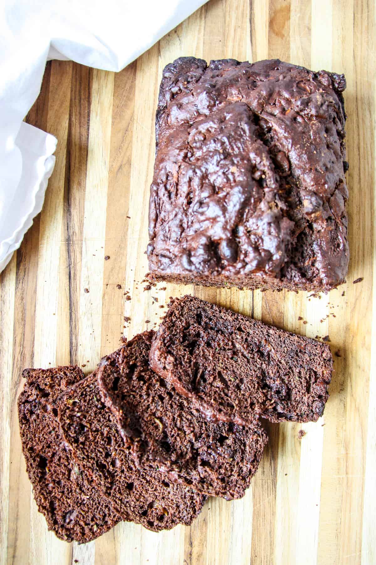 Gluten-free chocolate zucchini loaf sliced on a cutting board.