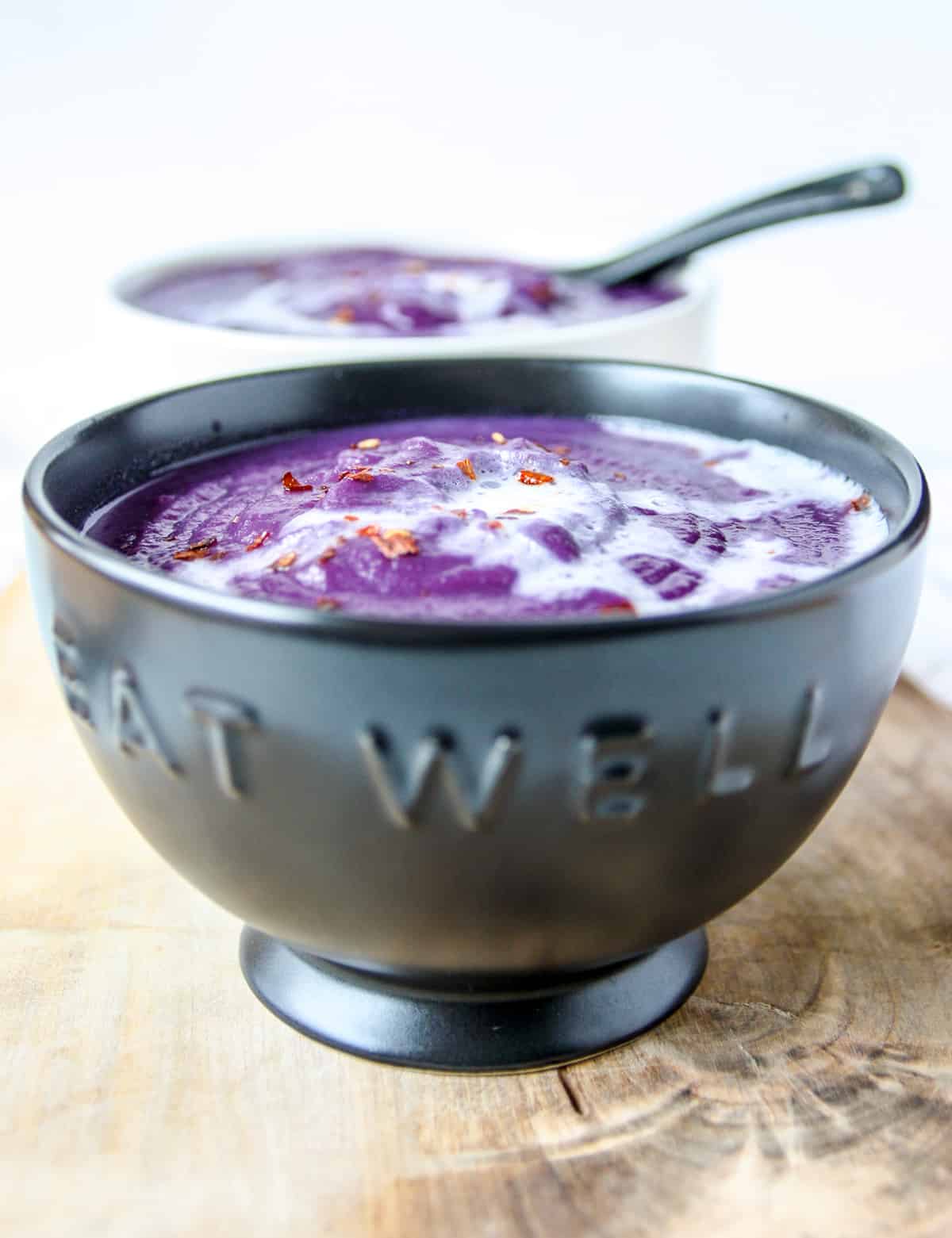 Red cabbage soup in a black bowl.