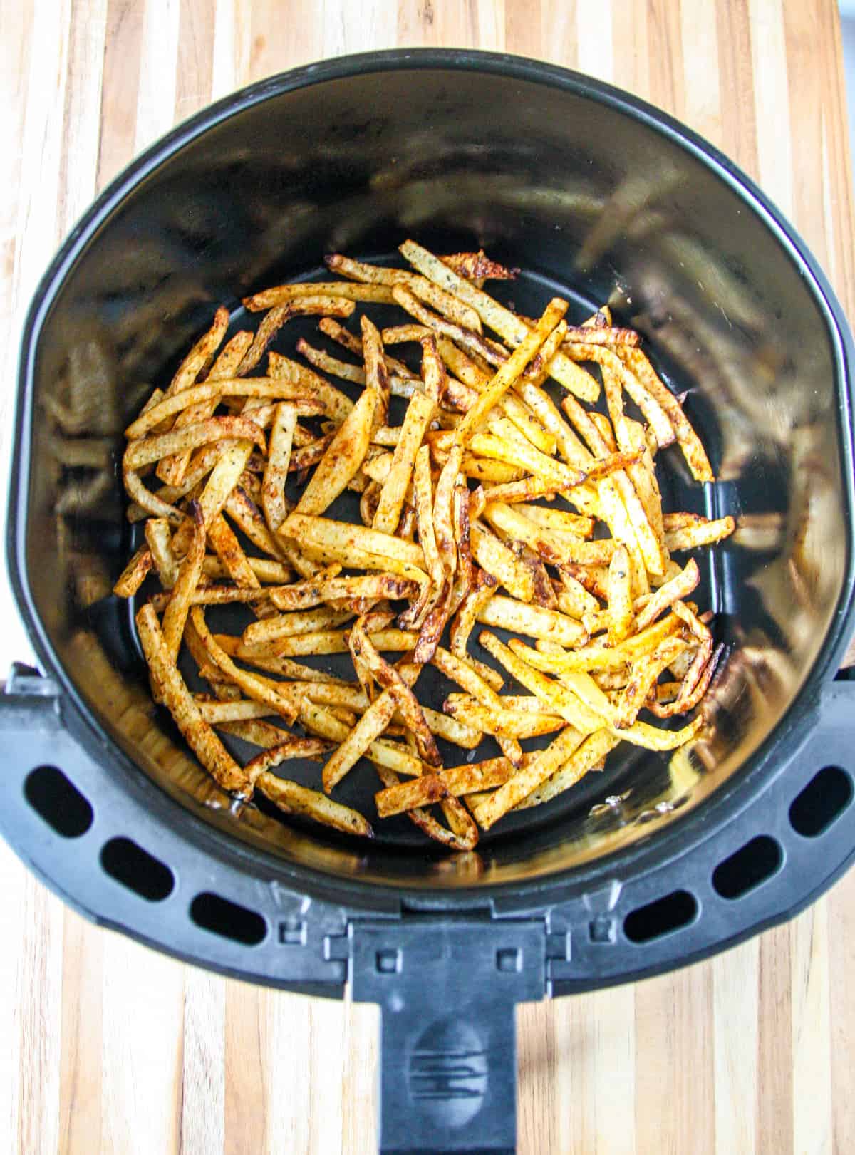 Cooked rutabaga fries in an air fryer basket.