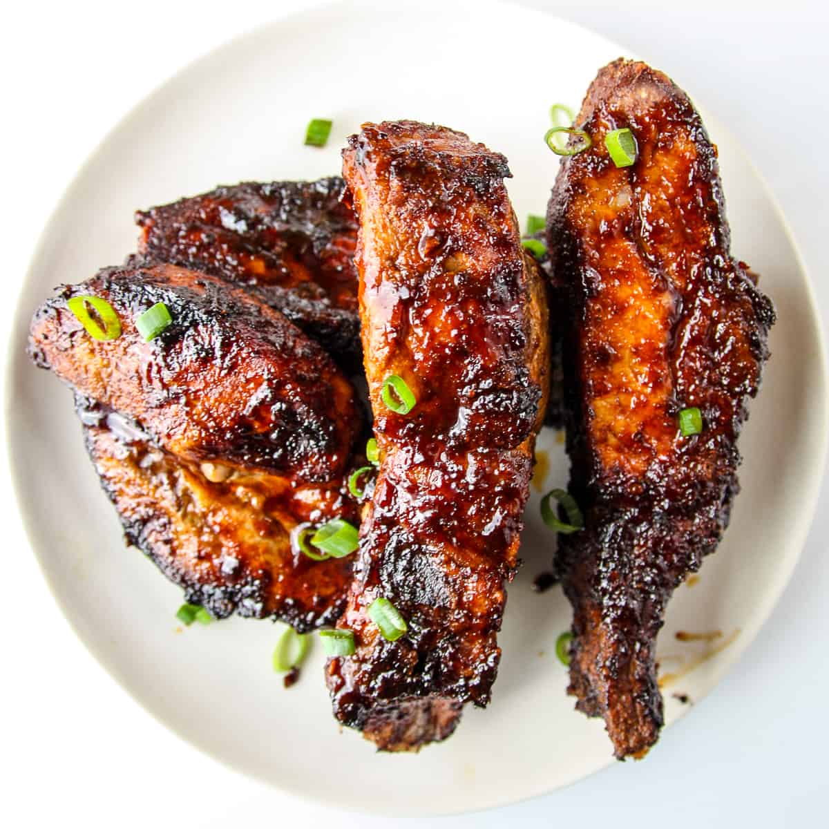 Sauce covered ribs on a white plate.