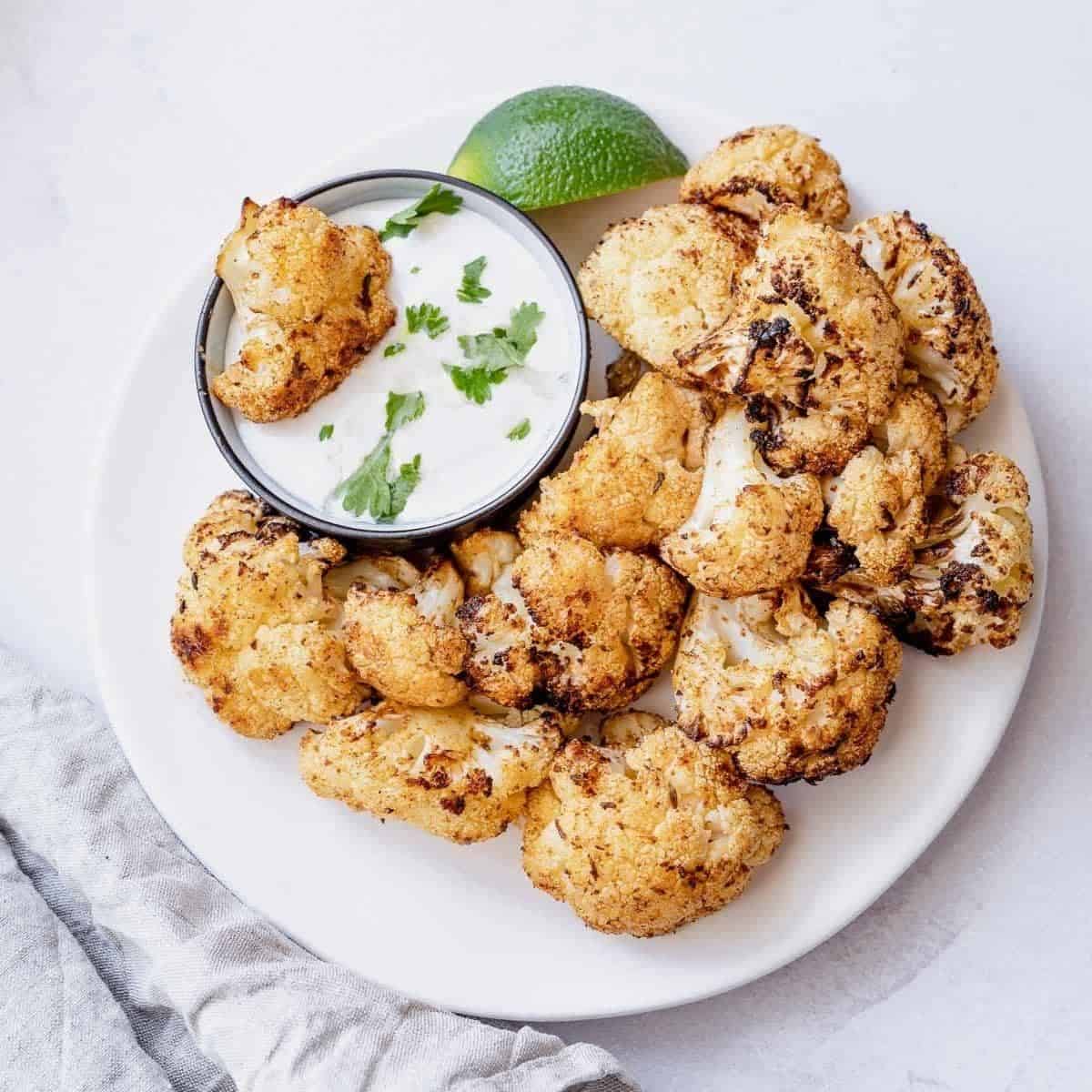 Air fried cauliflower florets on a white plate.
