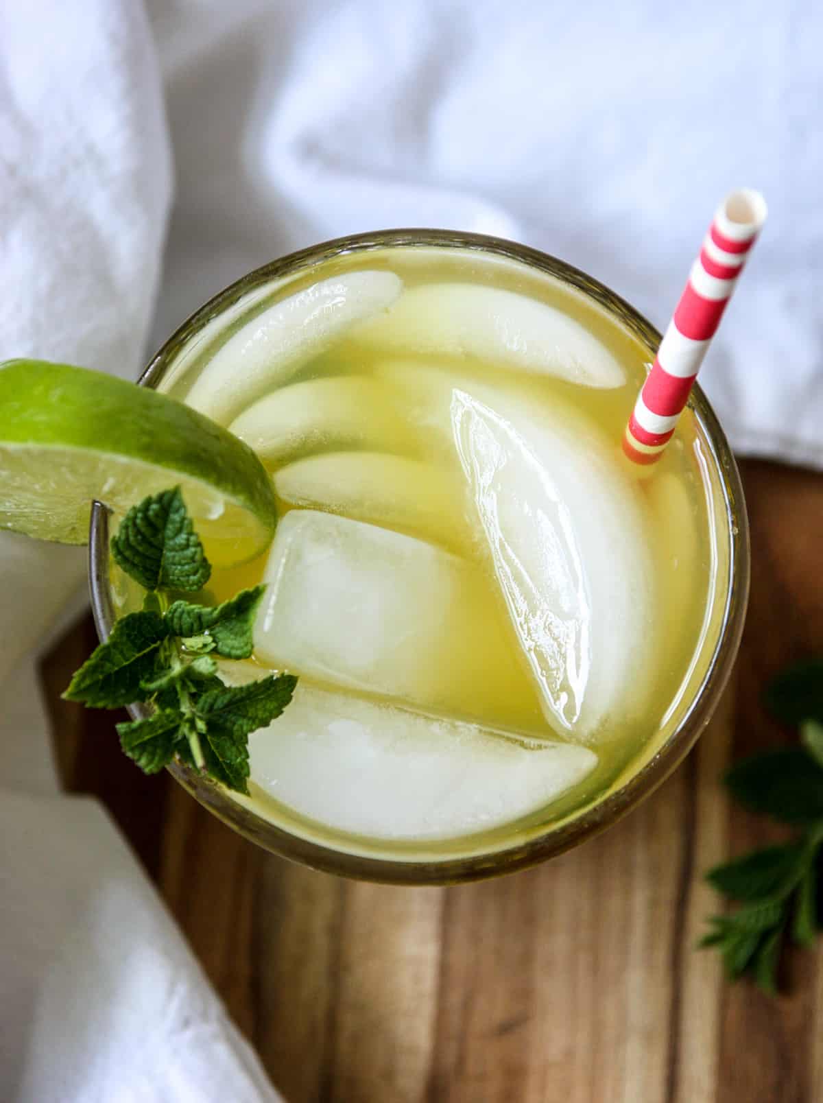 Top down view of the cocktail glass garnished with mint leaves and a lime wedge.