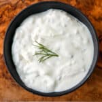 A black dish filled with tzatziki sauce.