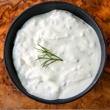 A black dish filled with tzatziki sauce.