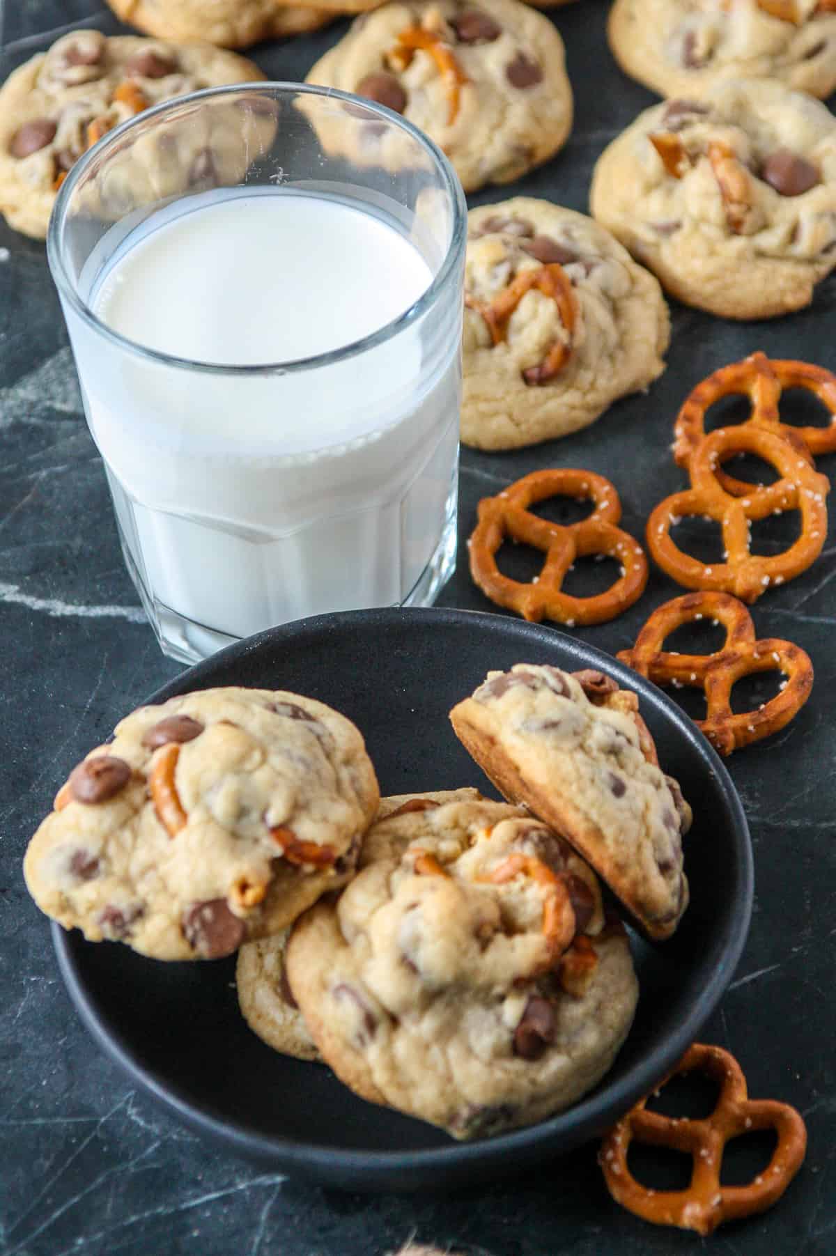 A plate of cookies and a glass of milk on a marble countertop.