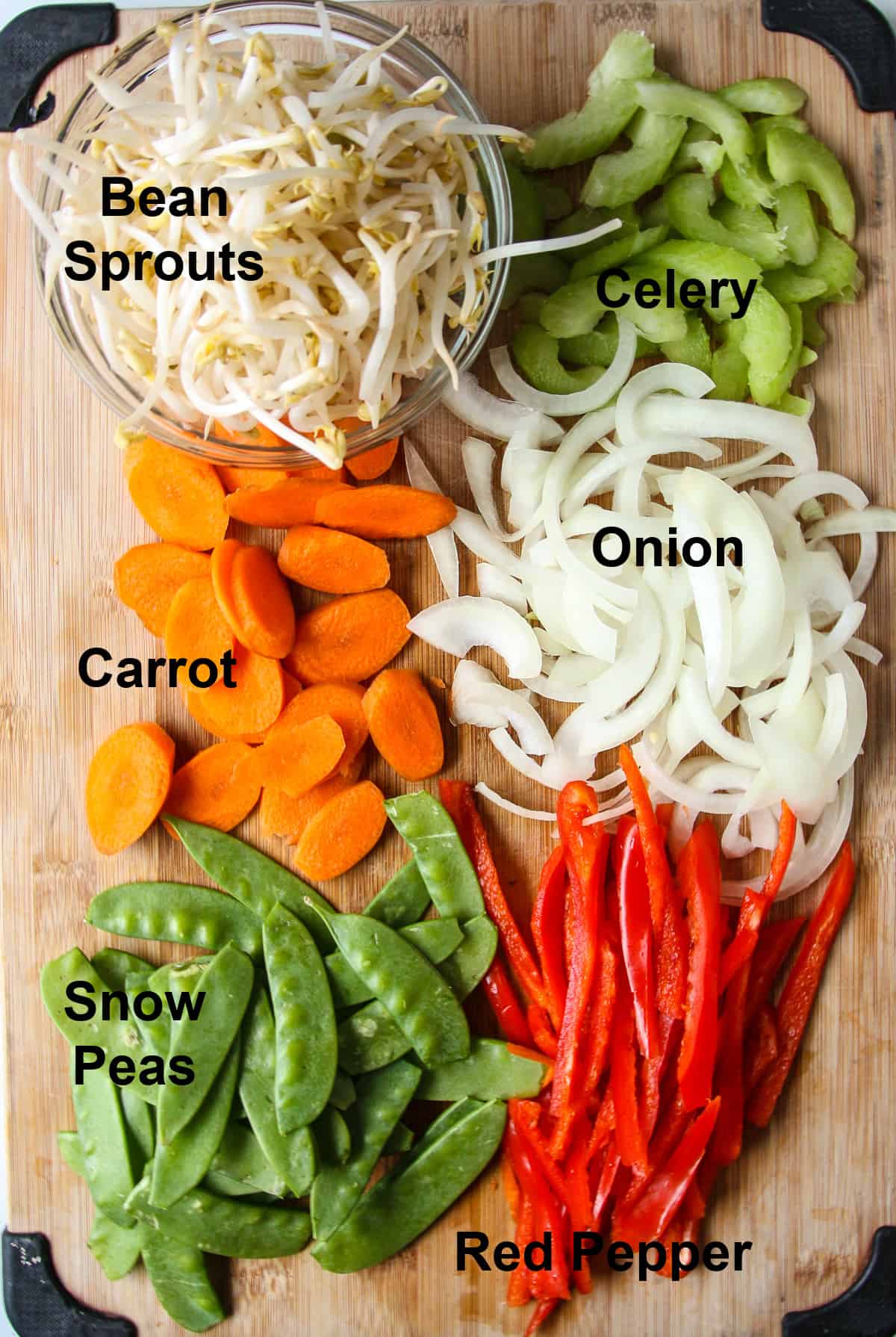 All of the chop suey vegetables chopped and ready to use on a wooden board.