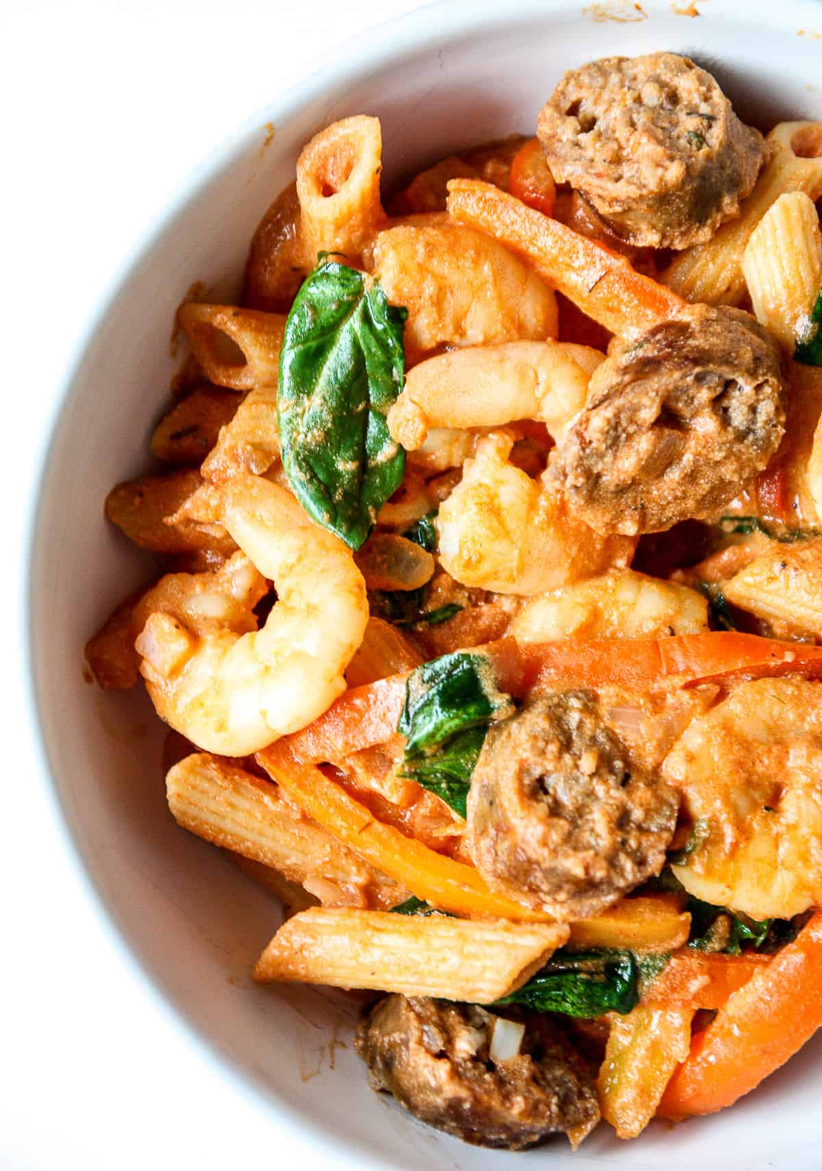 Cajun shrimp and sausage pasta in a white bowl.