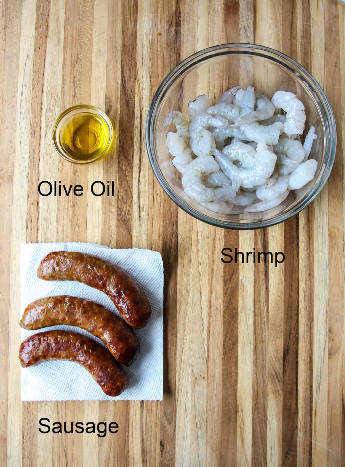 Sausage, shrimp and olive oil on a wooden board.