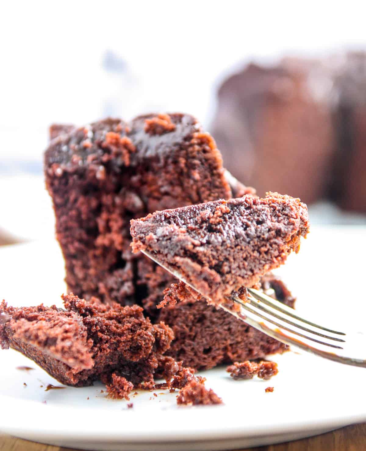 A close up of a fork full of chocolate cake.