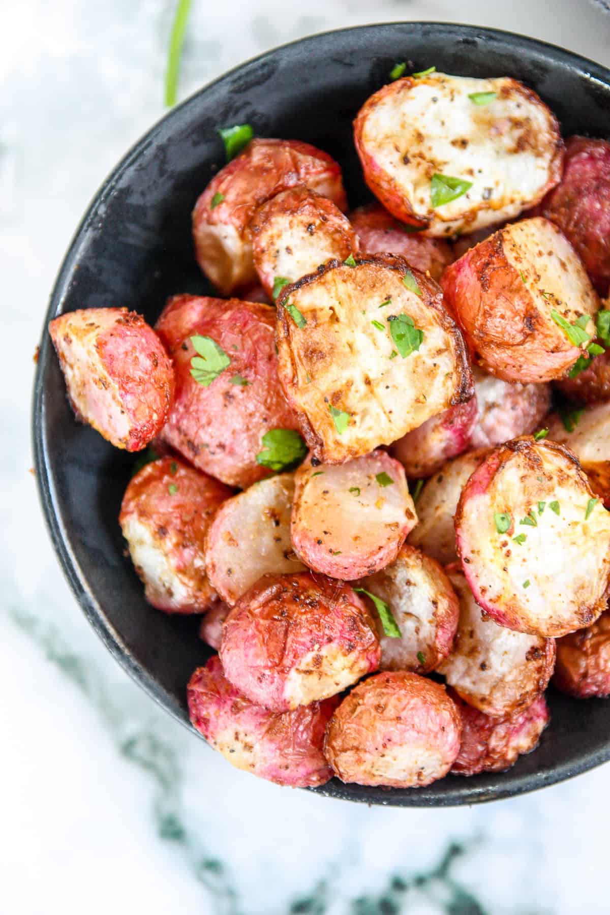 Air fryer radishes in a black bowl.