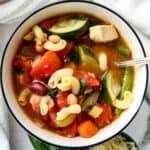 Chicken minestrone soup in a white bowl.