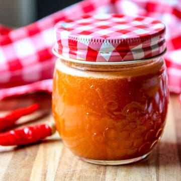 Cayenne pepper sauce in a glass jar with a red and white lid.