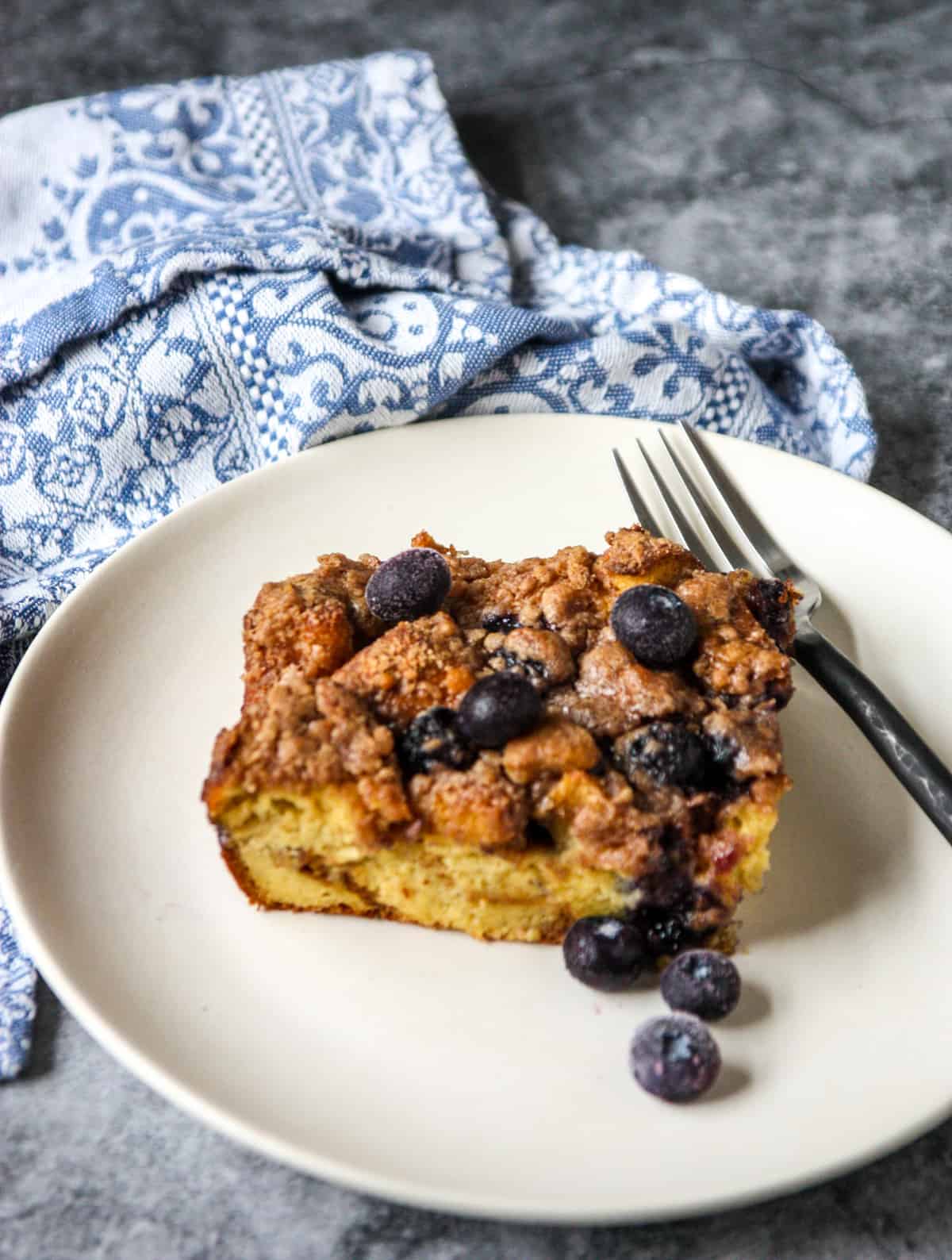 Blueberry brioche French toast on a white plate beside a blue and white napkin.