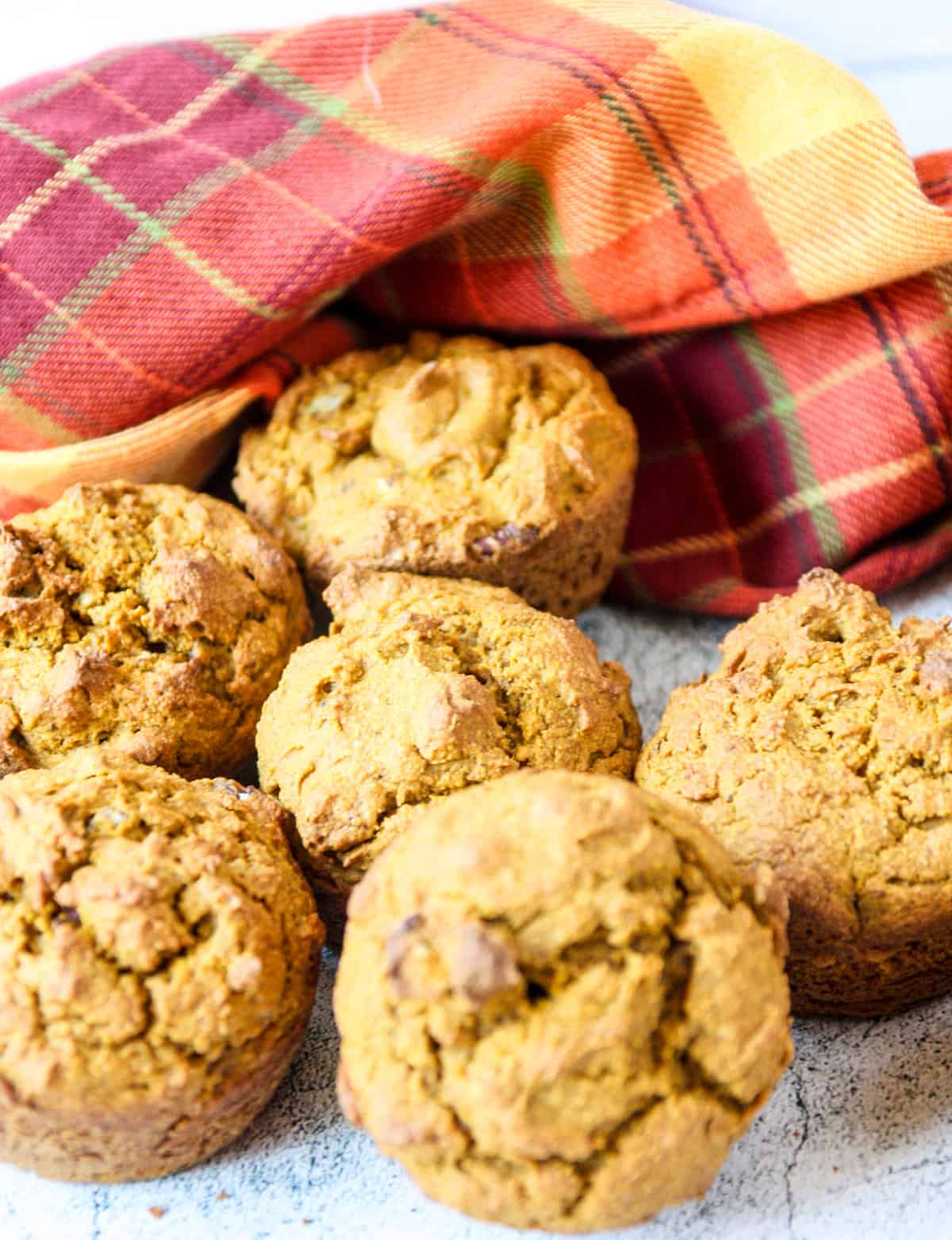 A half dozen oat flour pumpkin muffins on a marble counter top.