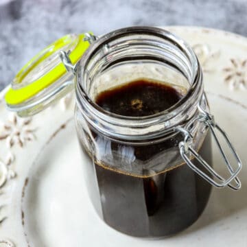 Gingerbread syrup in a glass jar with an open hinged lid.