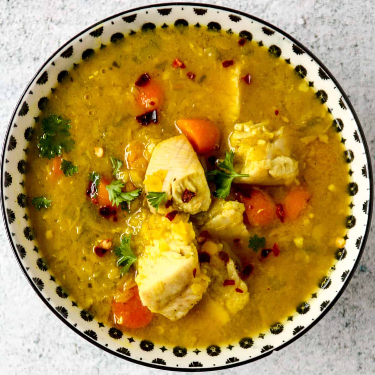 A black and white bowl filled with lentil and turkey soup.